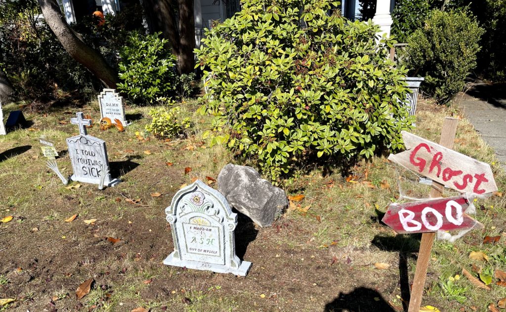 Front yard decorated to look like a grave yard, with fake head stones and signs that read "Ghost" and "Boo."