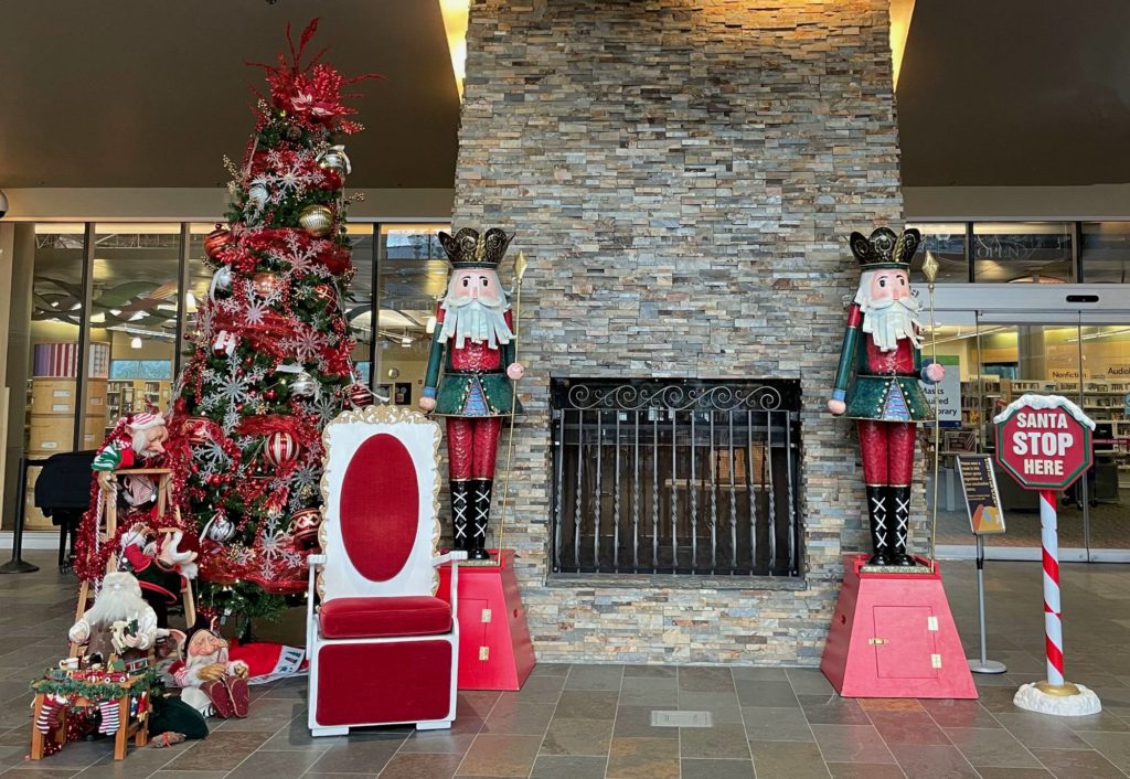 Christmas setting: decorated Christmas tree, wrapped presents, small Santa and elves, stone fireplace, 2 giant nutcrackers, sign "Santa stop here"