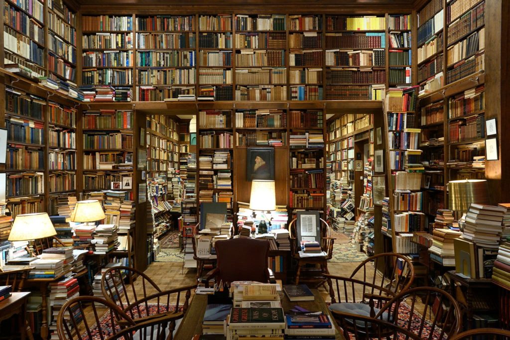 Photo of a huge, two-room library crammed with books, both on shelves and stacked between shelves.