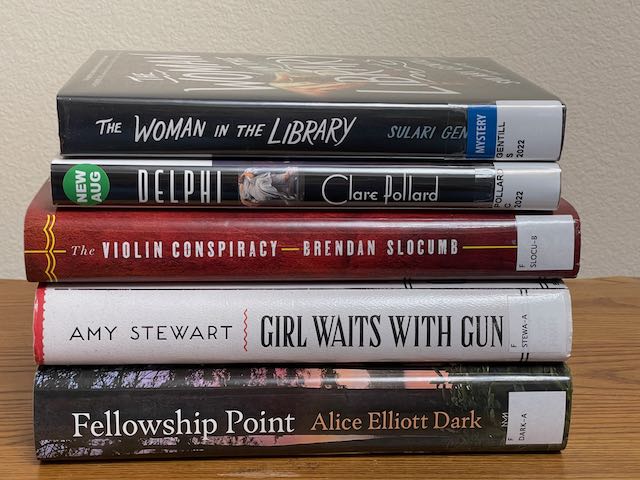 Stack of 5 books lying horizontally: The Woman in the Library by Sulari Gentill, Delphi by Clare Pollard, The Violin Conspiracy by Brendan Slocumb, Girl Waits with Gun by Amy Stewart, Fellowship Point by Alice Elliott Dark