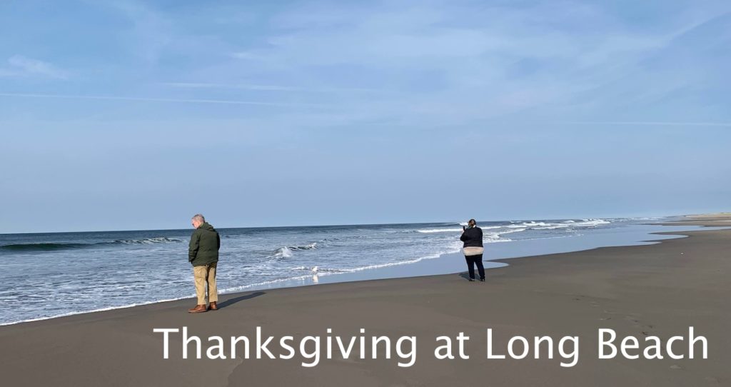 A man and woman on a sandy beach as ocean waves roll in. Text reads "Thanksgiving at Long Beach."