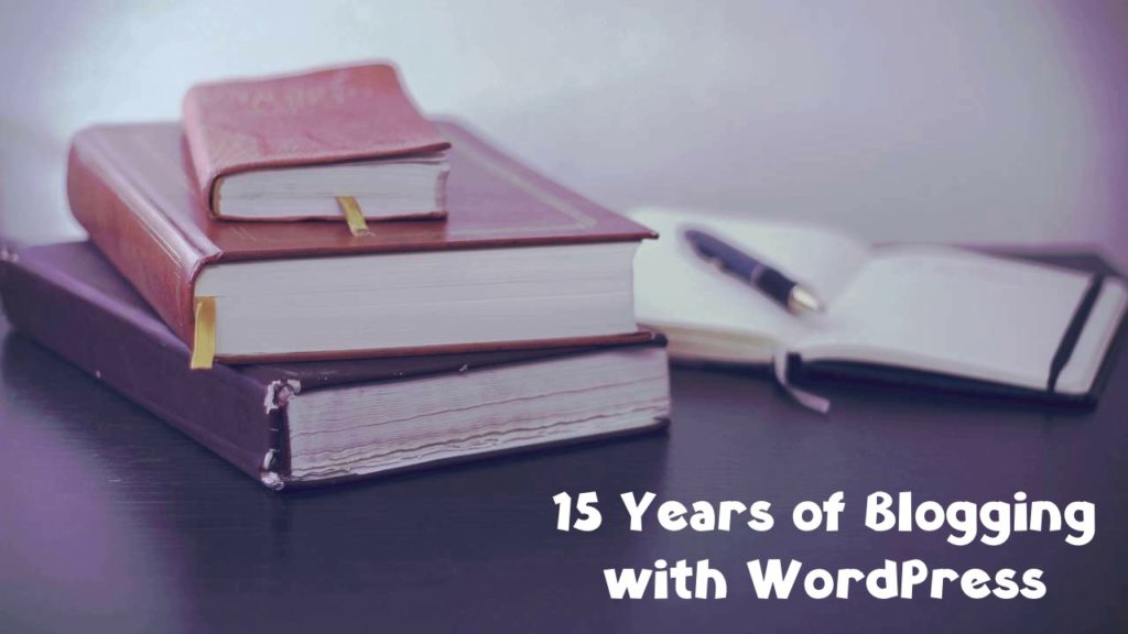 A stack of three closed books. Next to them lies an open notebook and a pen. Title: 15 years of blogging with WordPress.